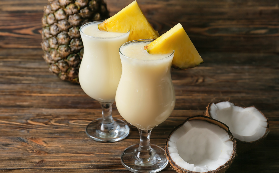 Pina Colada cocktails with a pineapple garnish on a wooden table