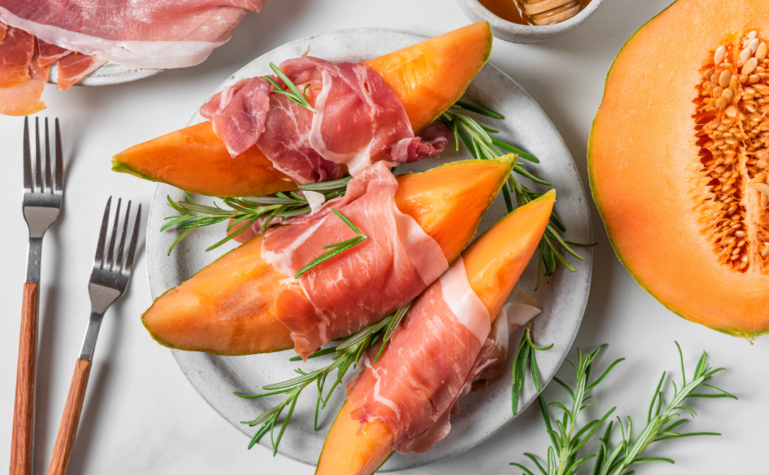 Melon slices wrapped in parma ham, garnished with rosemary sprigs