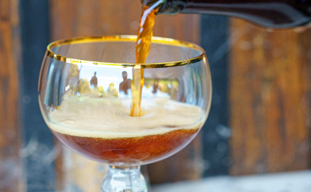 A glass beer goblet, being filled with beer