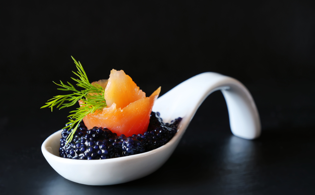 Black caviar topped with a bundle of smoked salmon and garnished with a dill sprig