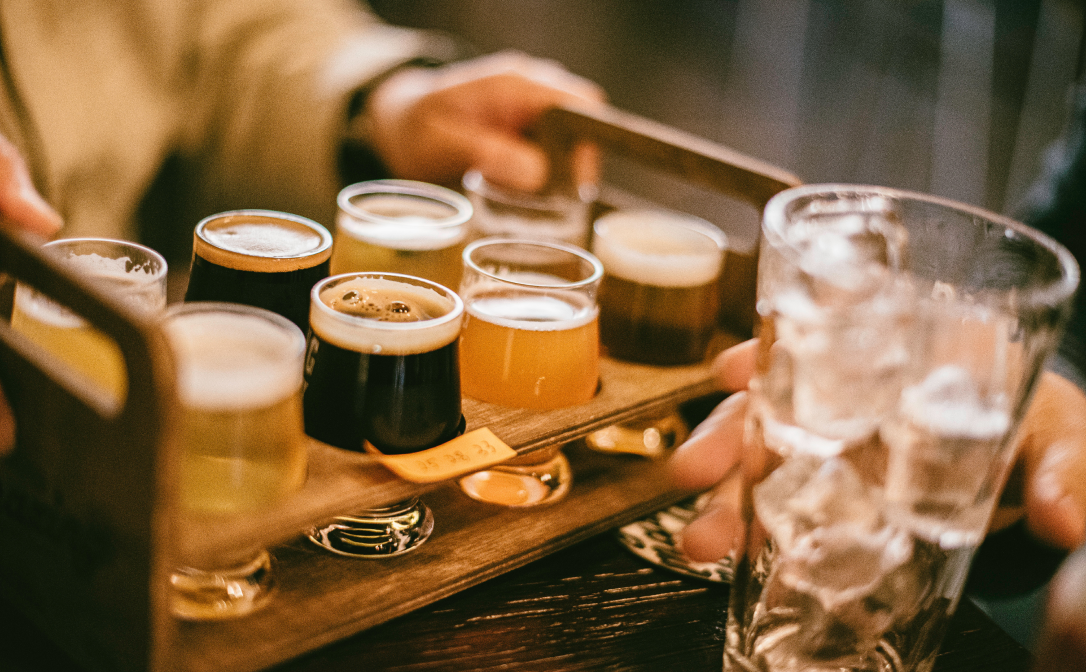 A wooden tray with different kinds of craft beer in clear glasses