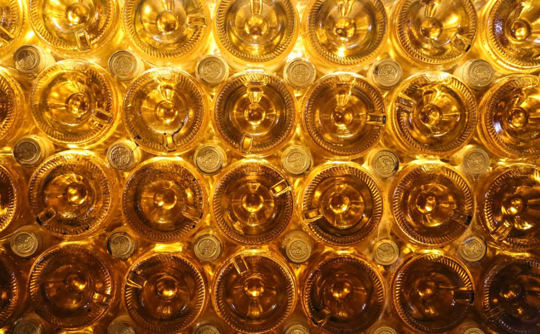 A stack of clear glass bottles filled with golden-coloured wine