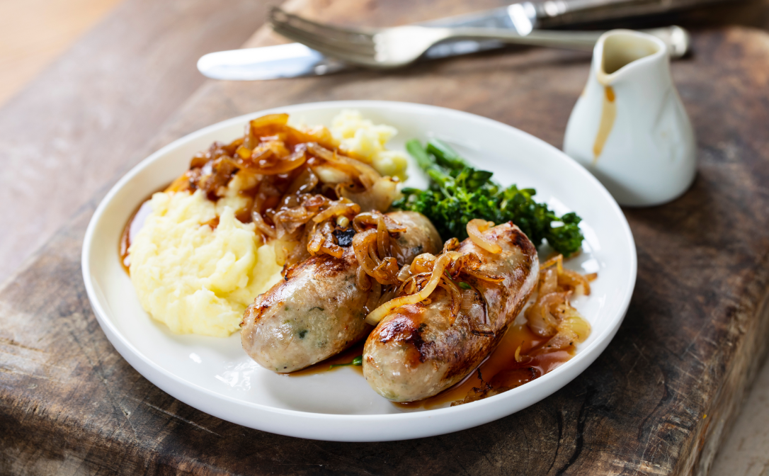 Pork sausages and mashed potatoes on a white plate